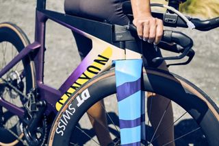 A woman sits on the top tube of a Canyon Speedmax CF SLX Hawaii LTD, emphasis on the blue design on the fork