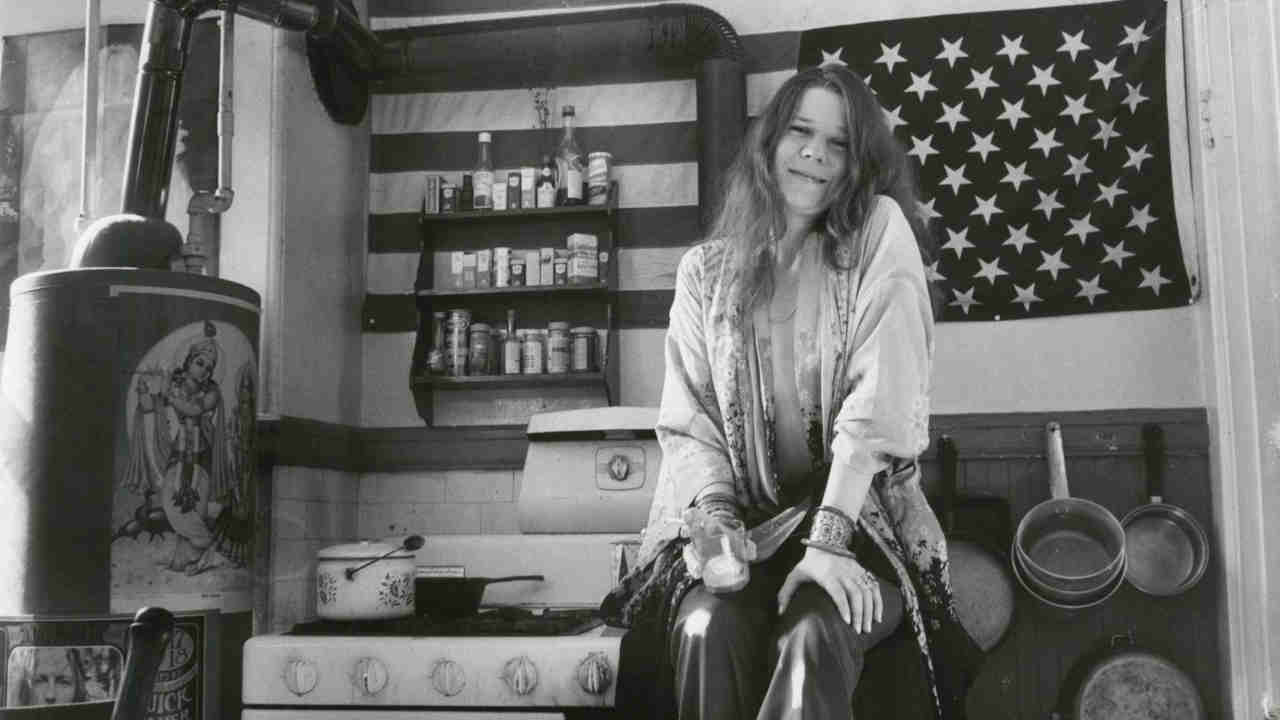 Janis Joplin posing for a photograph in front of a Stars And Stripes flag in 1969