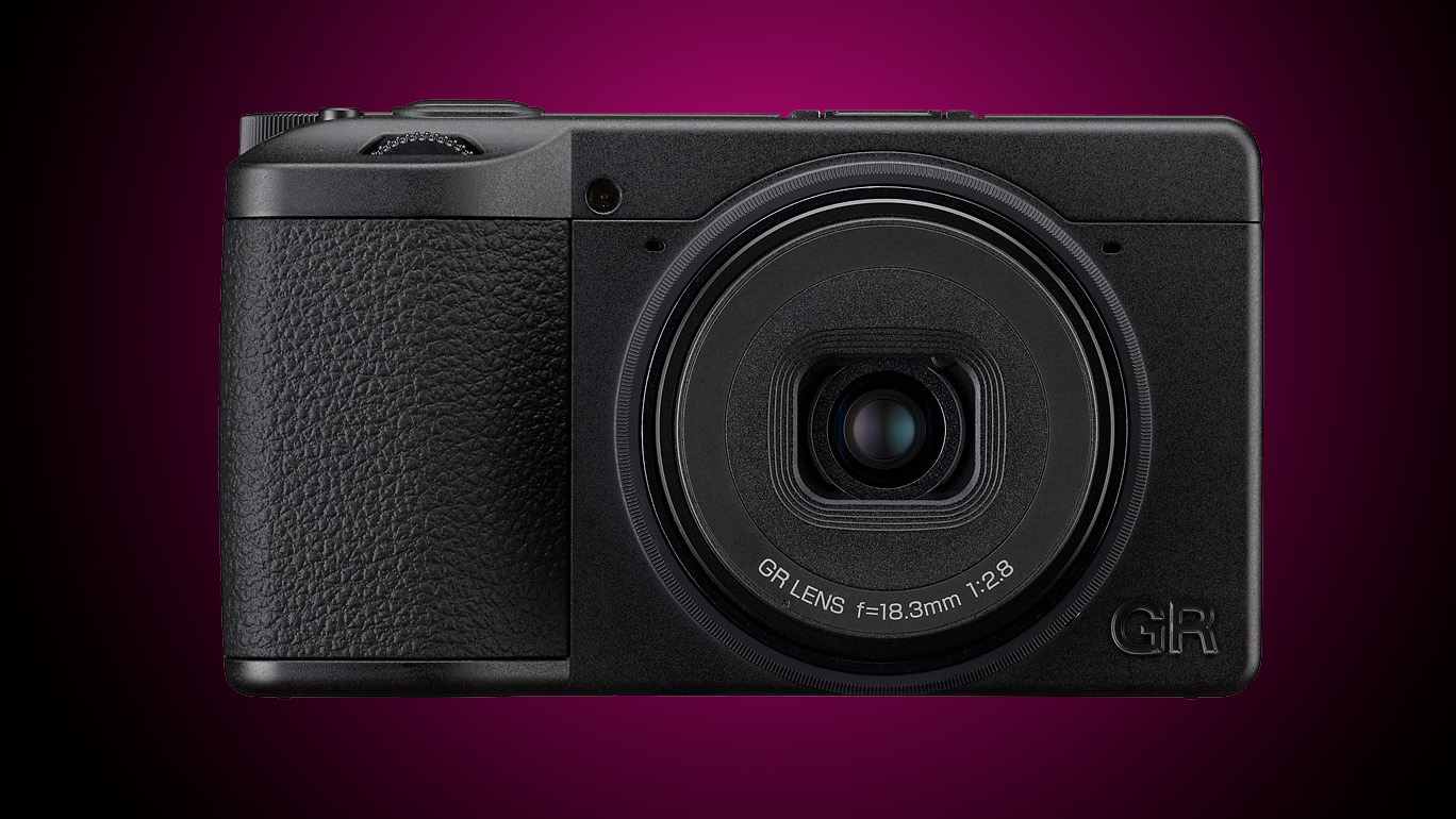 A Ricoh compact camera against a gradated purple background
