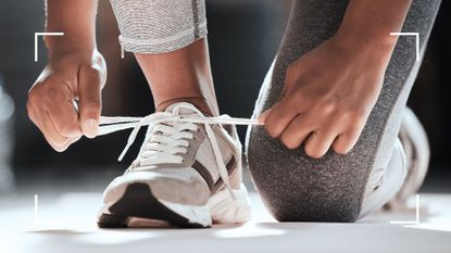 Woman tying up shoelaces wearing Fitbit on ankle, about to go out for a run