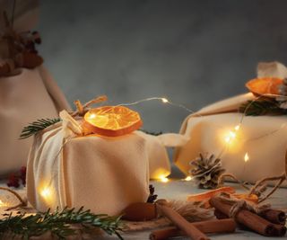 fabric wrapped gifts topped with dried orange slices and surrounded by fairy lights
