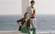A man and woman wearing a selection of clothing available from Brooks Brothers with the sea behind them.