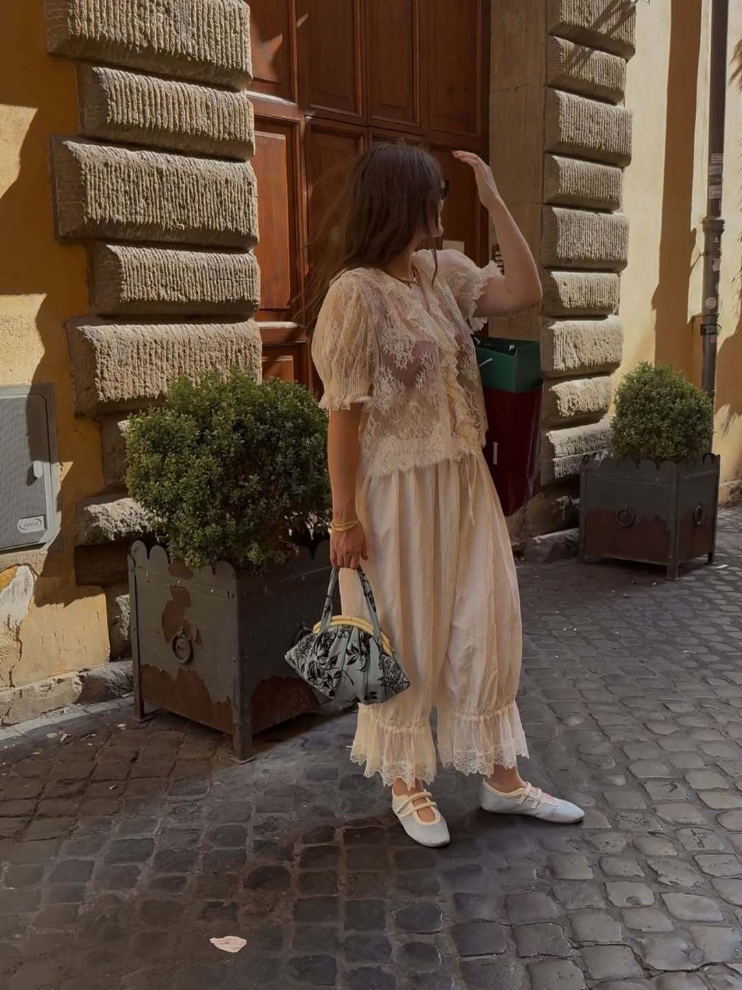 Fashion person Alessandra Garcia wears a winter sun outfit. She wears a lace top and lace trouser outfit.