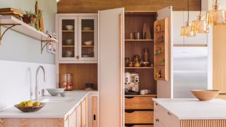 A kitchen with a built in pantry, quartz countertops and glass pendant lights