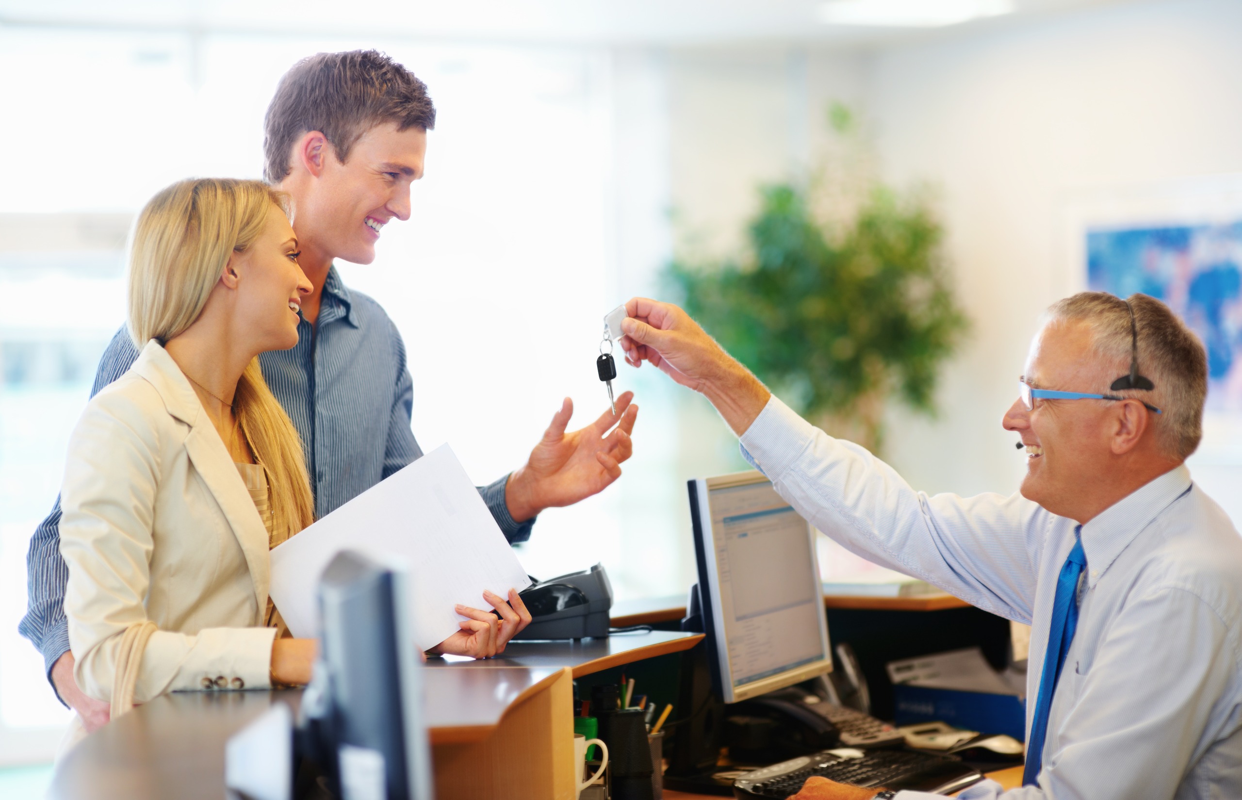 A couple receives keys from a customer service representative after renting a car.