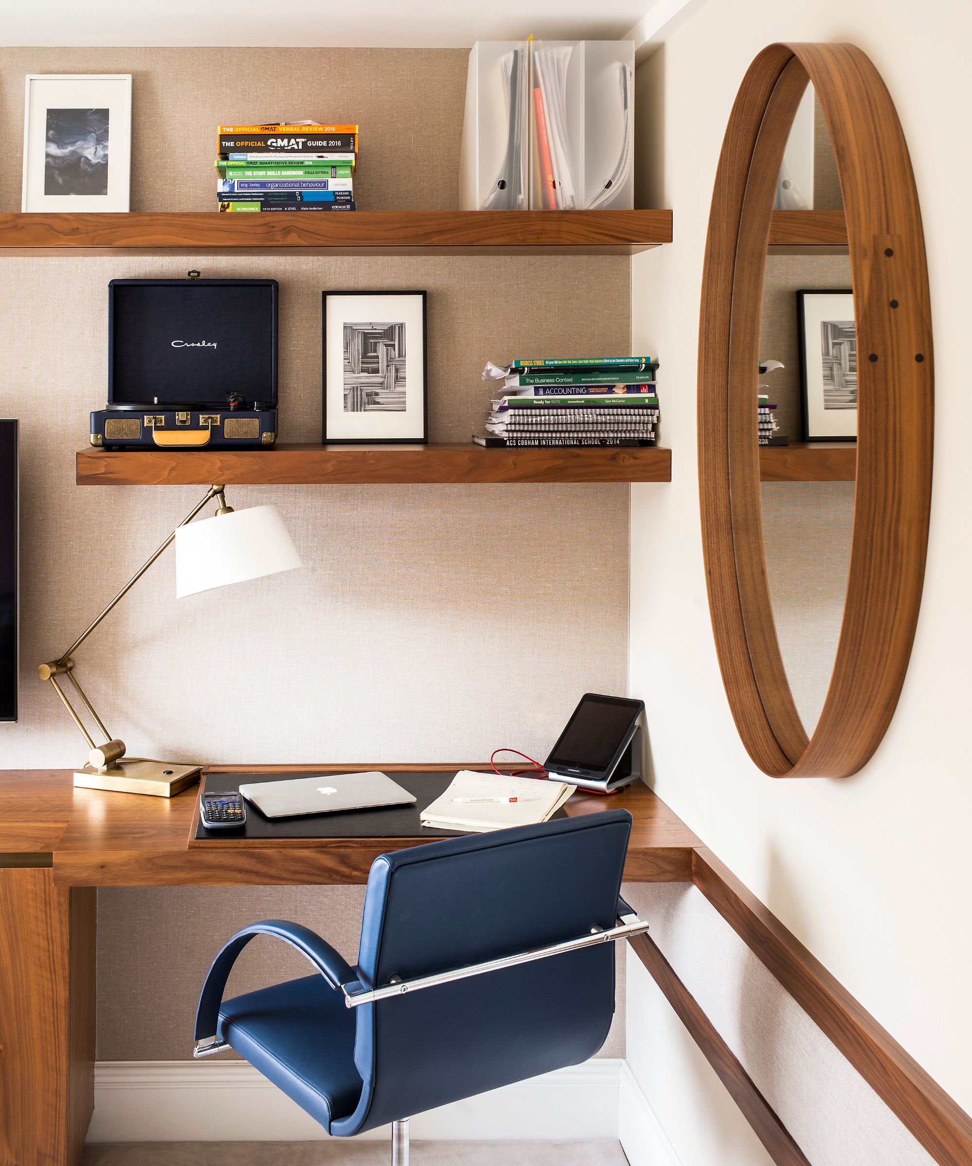 Home office with wood desk, shelves and mirror and blue chair