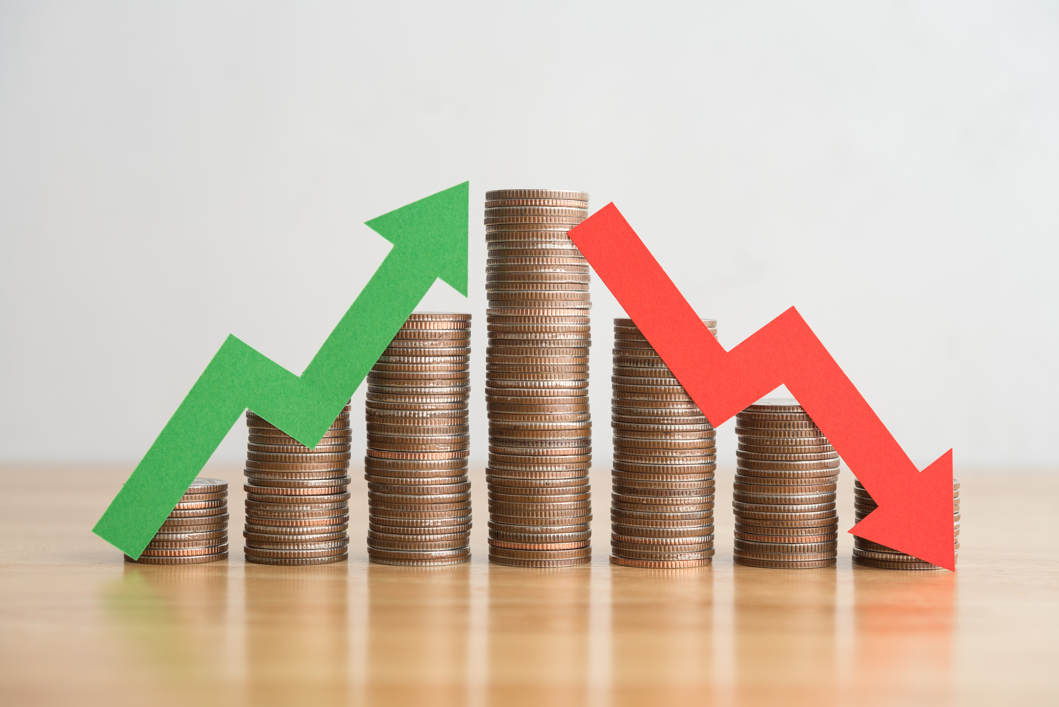 Ascending stacks of coins with a green arrow and descending stacks of coins with a red arrow