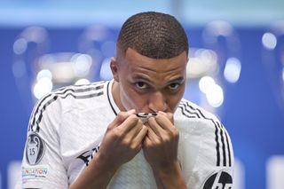 Kylian Mbappe kisses the badge on his Real Madrid shirt at his official presentation in July 2024 as Alphonso Davies considers free move from Bayern Munich.