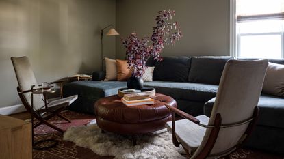 cozy living room with green walls, layered rugs, multiple seating arrangements, fall foliage, lighting