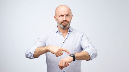 picture of impatient man pointing at his watch