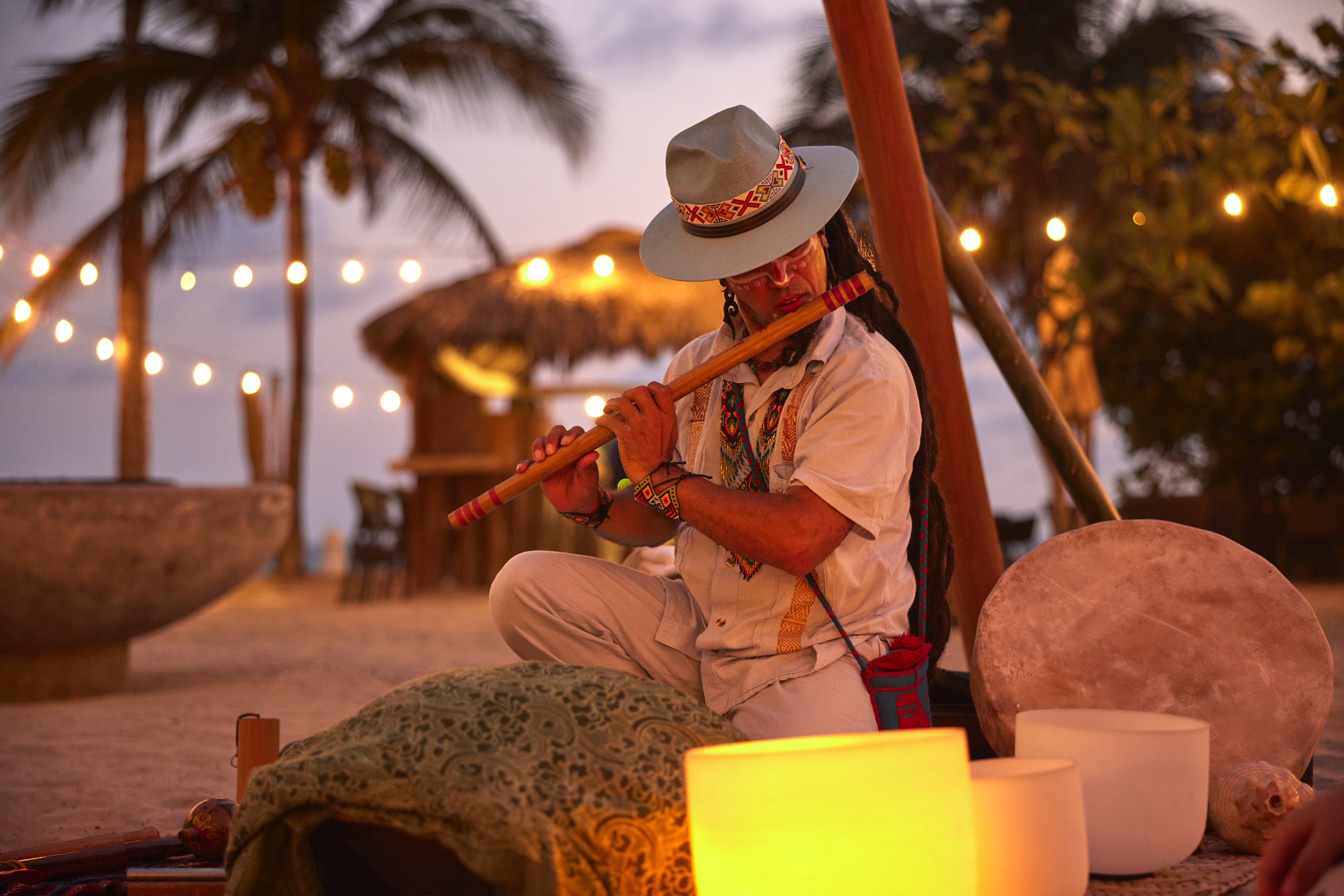 A man plays the flute during a sunset beach cacao ceremony at W Punta de Mita