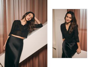 Camila Mendes poses for photos wearing black sheer top and black silk skirt.