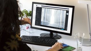 En kvinna sitter vid sin dator och använder Pixlr X