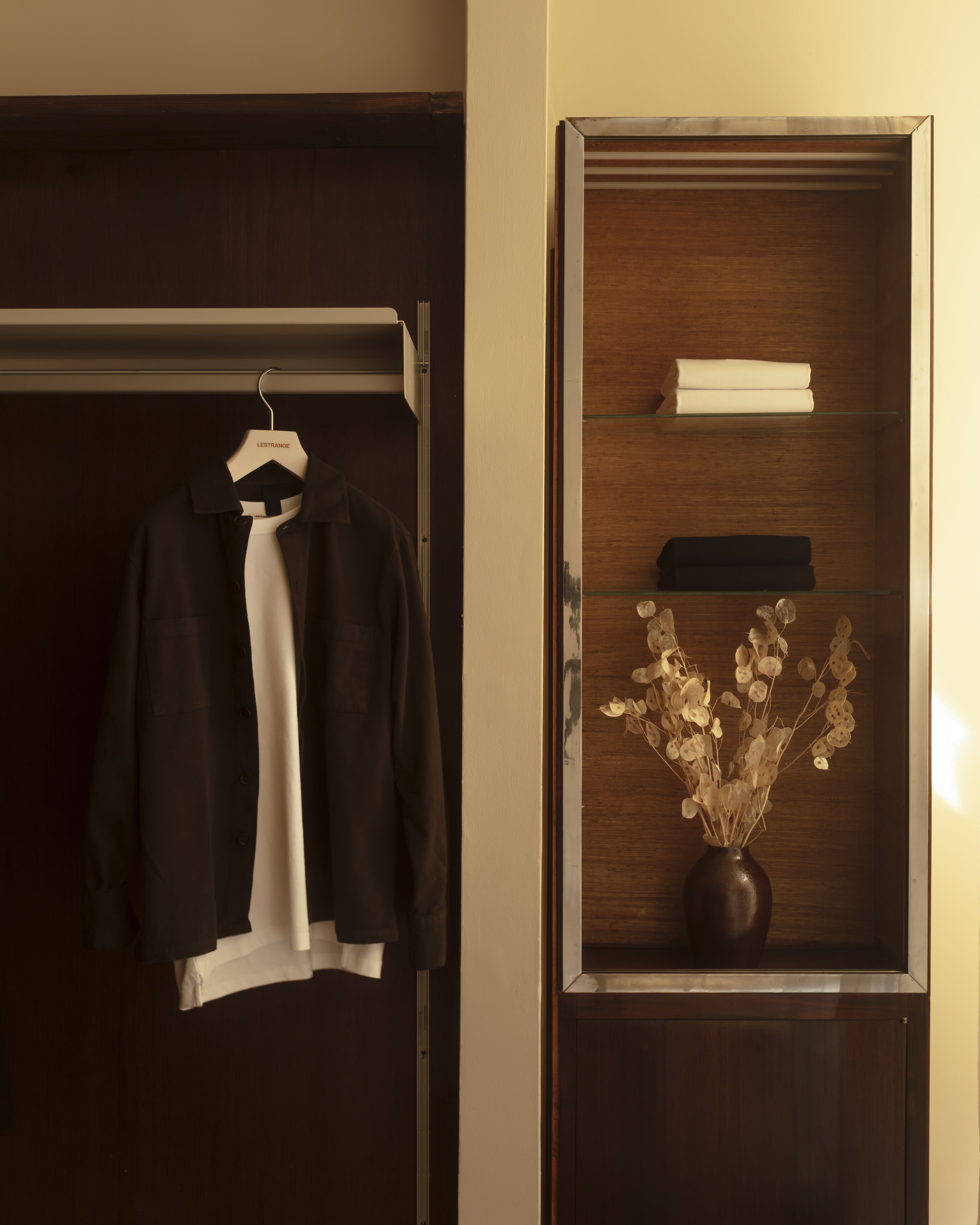 Different corners of a sleek menswear store clad in warm woods, beige drapery, and silver and mint green accents.