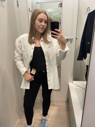 Woman in mirror wears black top, white shirt and black jeans