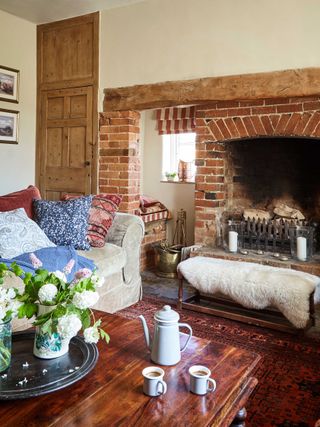 A farmhouse living room with brick fireplace, wooden doorway and sofas