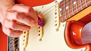Man playing an electric guitar with a purple guitar pick