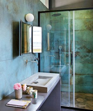 bathroom with blue gray tiling, concrete basin and shower with glass enclosure