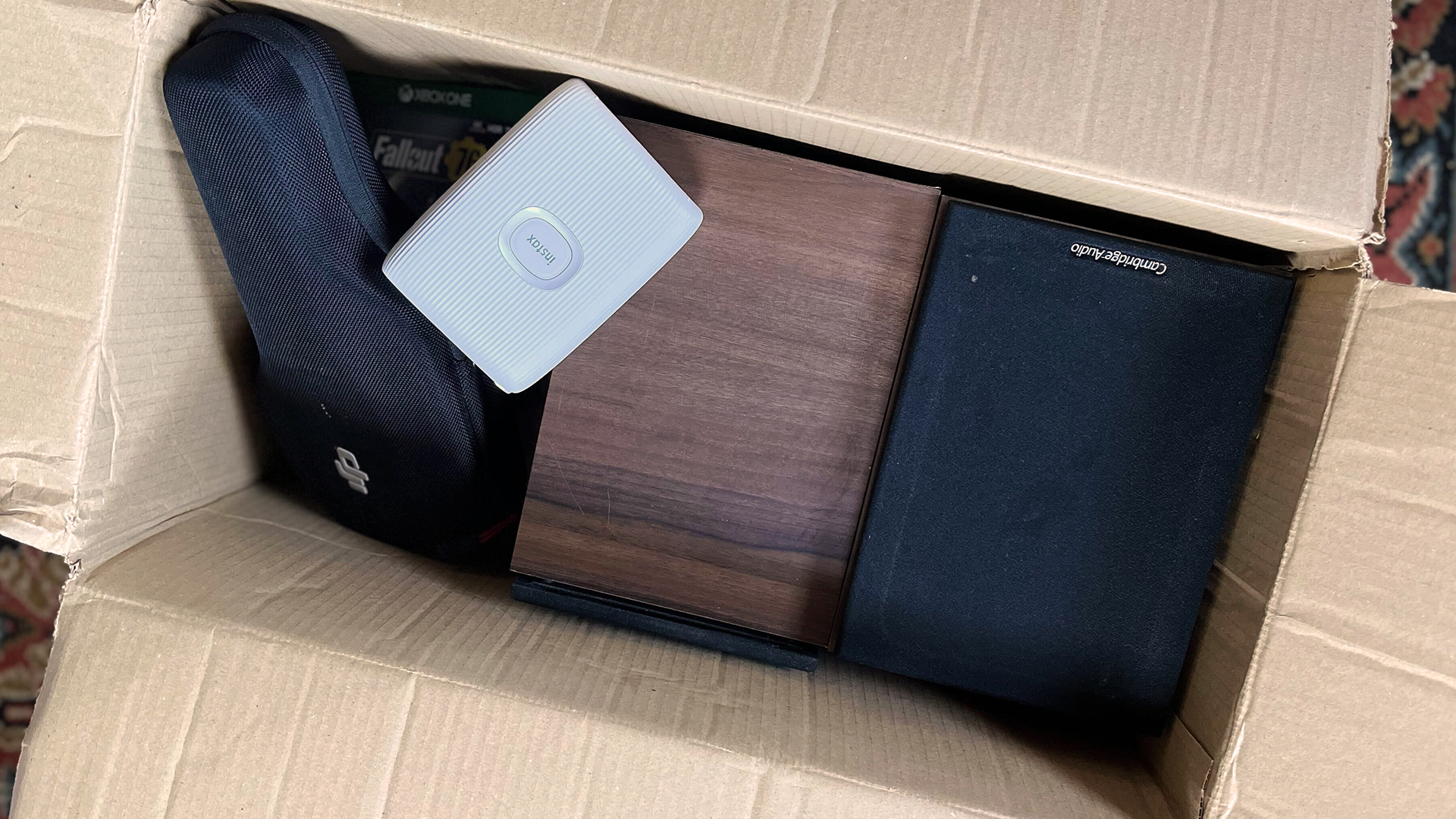 A cardboard box of old tech, showing Cambridge Audio speakers, DJI Osmo+ and Instax Mini printer