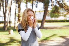 Woman with a hay fever blowing her nose