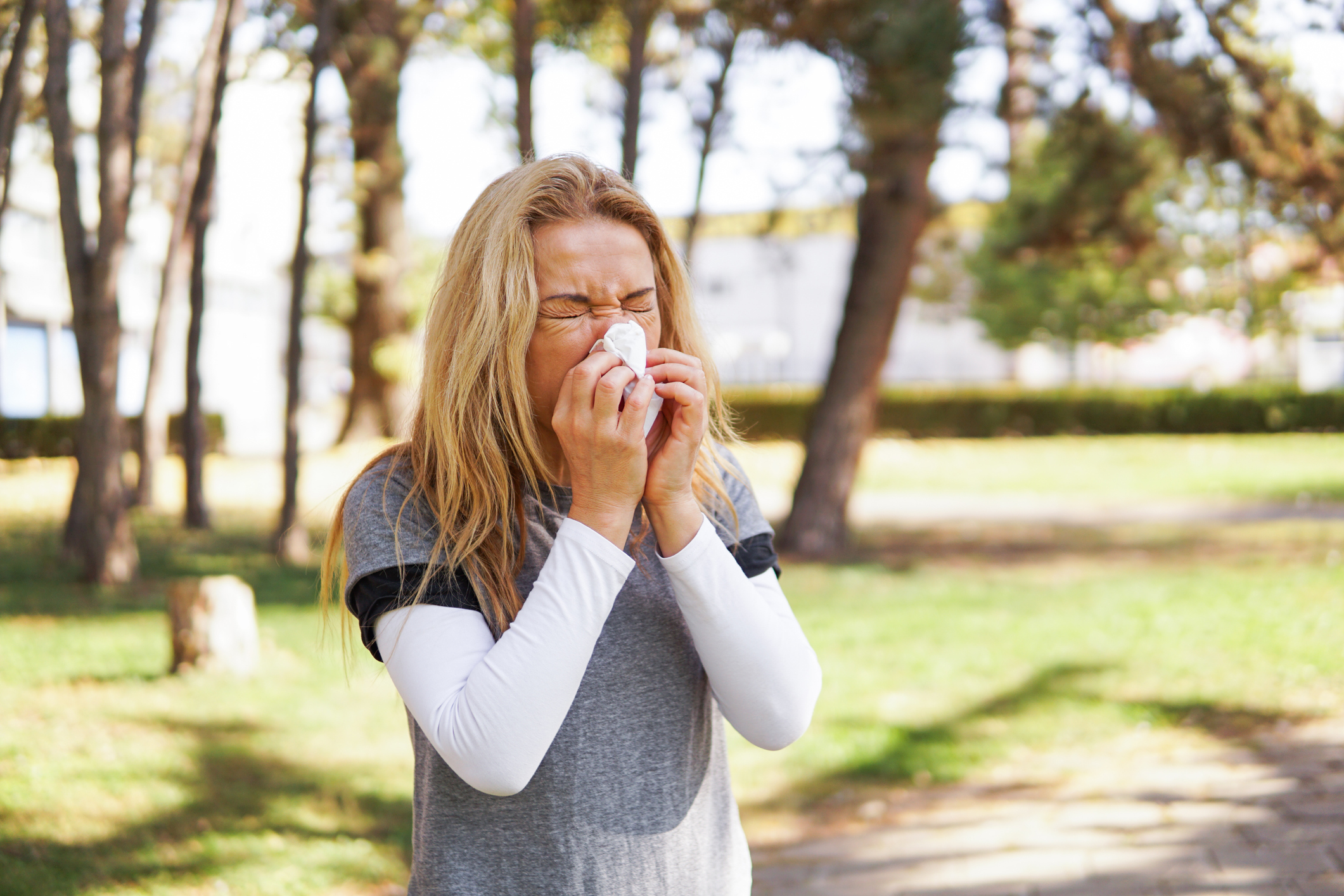 Woman with a hay fever blowing her nose