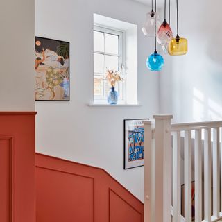 Colourful glass pendant lights over a staircase with panelled walls