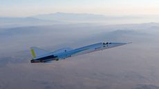 a needle-nosed white and silver plane flies over a desert-mountain landscape