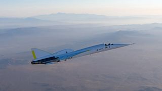 a needle-nosed white and silver plane flies over a desert-mountain landscape