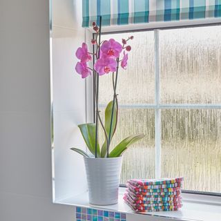 Obscured bathroom glass with pink flower vase and set of towels