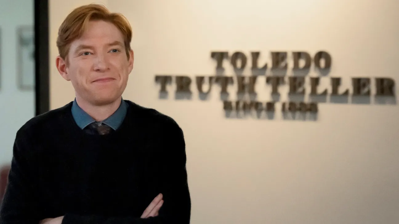 Domnhall Gleeson se para frente a una señal para el periódico Toledo Truth Teller