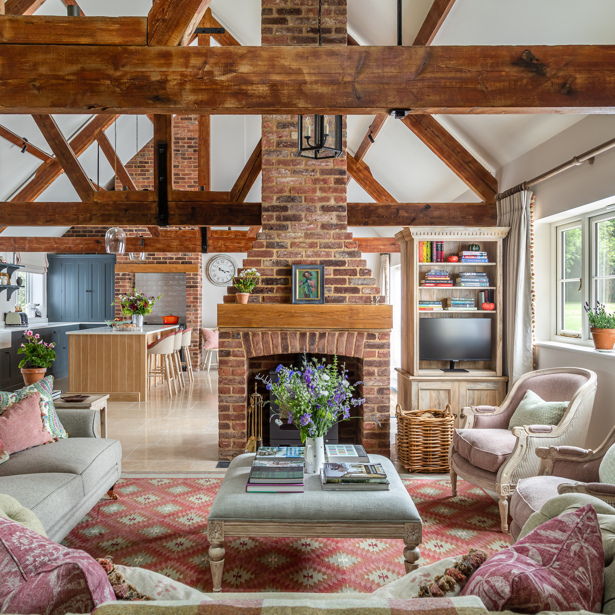 sitting area in barn conversion with exposed wooden ceiling beams, brick fireplace and chimney and upholstered seating