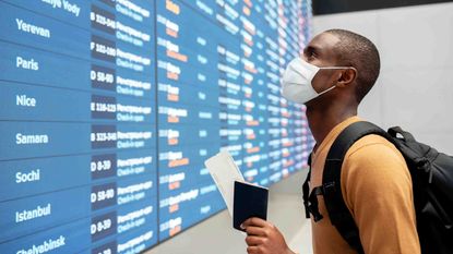 A man in a mask looks at airline destinations