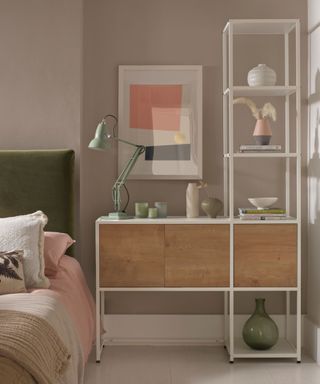 A gray bedroom with a wooden shelf and desk and green and pink bed