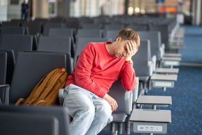 Tired sleeping man collapses against chair in airport waiting zone. Lengthy layover dragging on, exhaustion from waiting, delayed flight, overwhelming sleepiness, low spirits from endless airport time