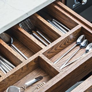 inside of wooden cutlery drawer with knives, forks and spoons