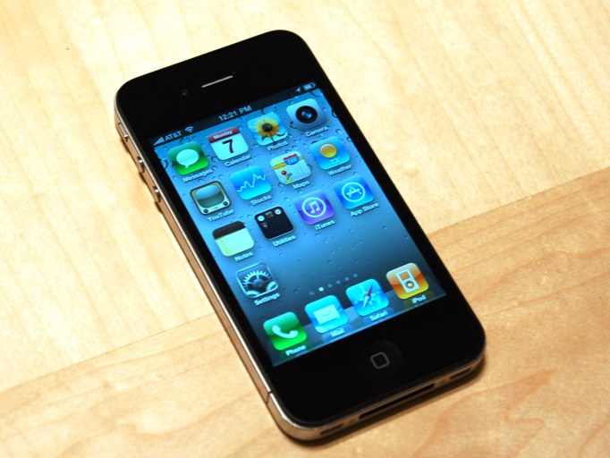 An iPhone 4 laid down on a wooden table