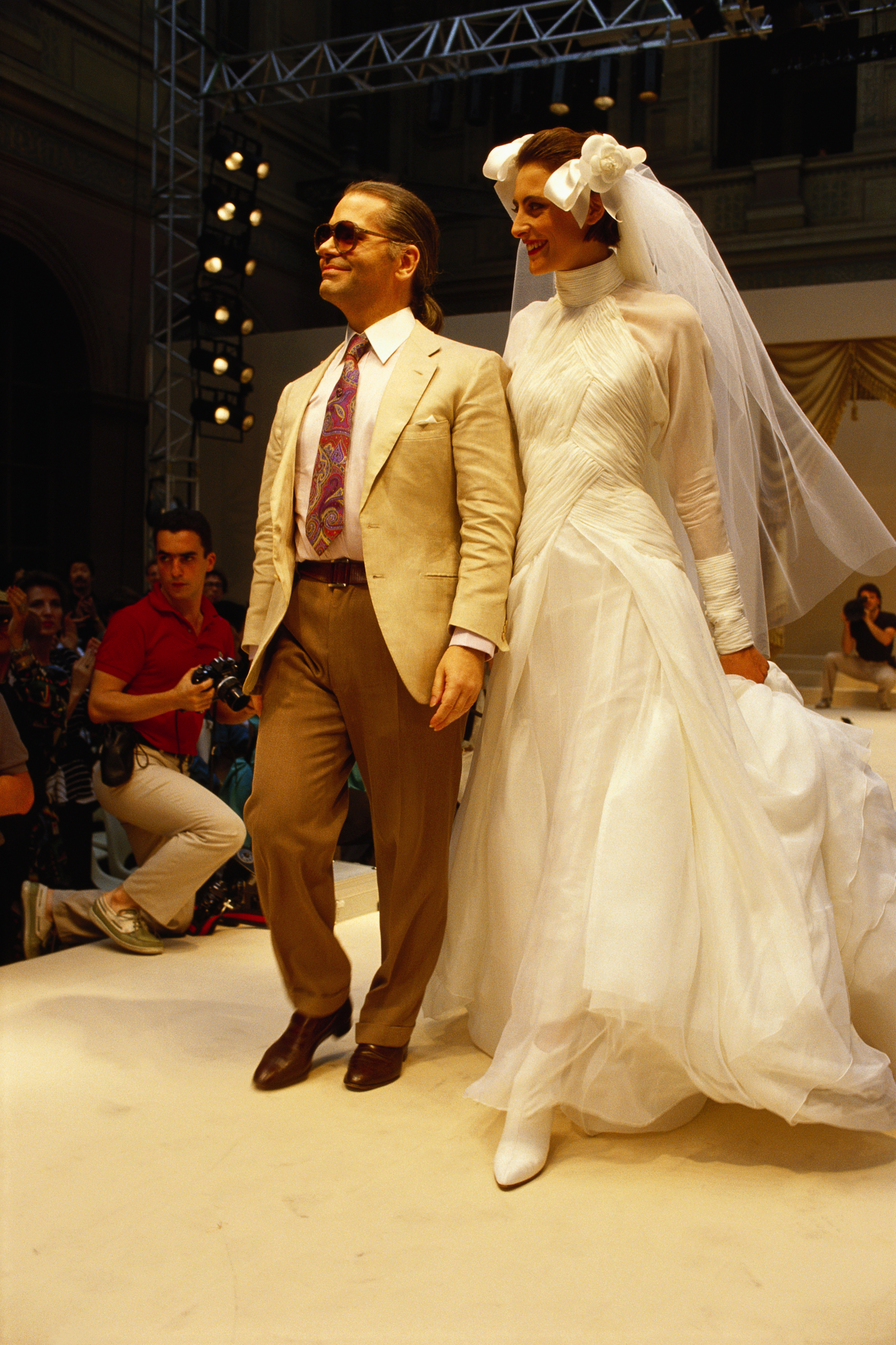 French fashion model Ines de la Fressange walks alongside German fashion designer Karl Lagerfeld, donning his haute couture wedding dress and veil for French fashion house Chanel at the 1986-1987 Fall-Winter fashion show. (Photo by Pierre Vauthey/Sygma/Sygma via Getty Images)