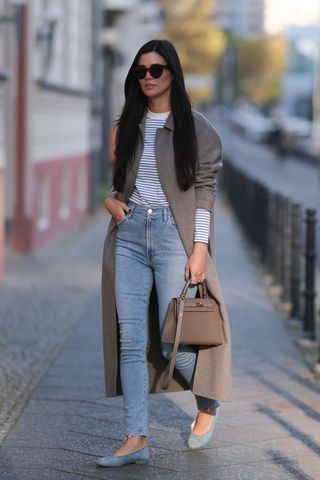 A street styler wearing a long coat and blue jeans