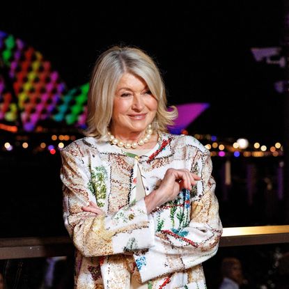 a white woman with short hair posing for a photo in front of the Sydney Opera House at night