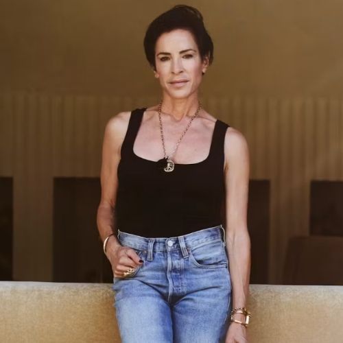 Image of someone in jeans and a black tank top standing in a butter yellow room.
