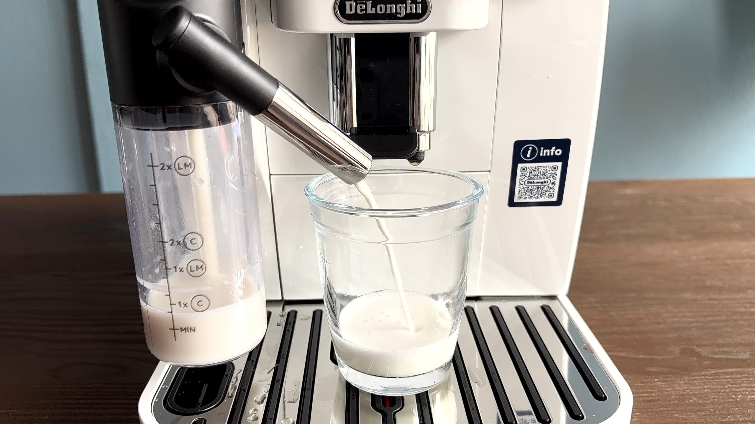 Milk pouring into glass cup from De'Longhi Magnifica Start