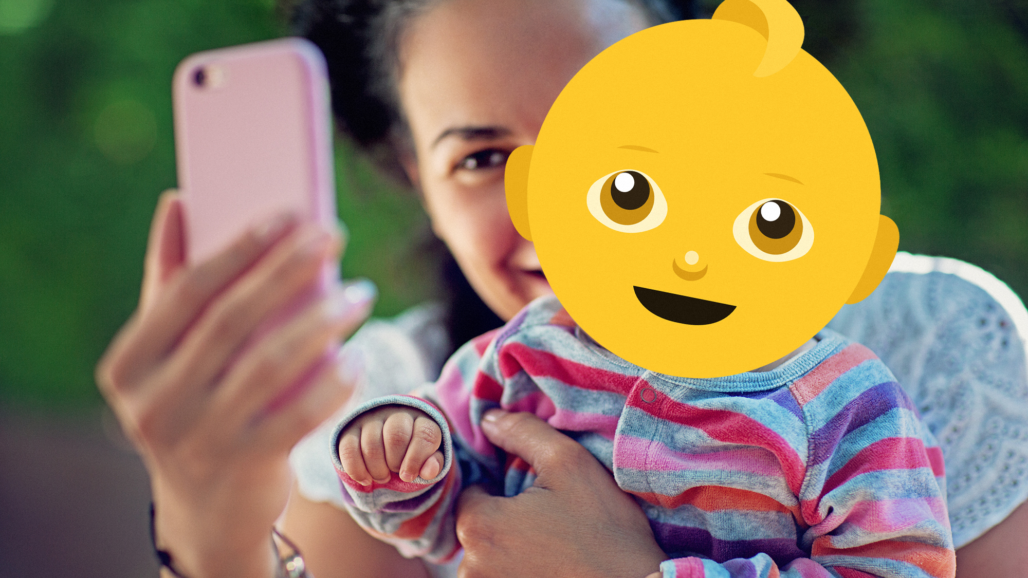 Mother taking selfie while holding baby, with the child's face covered by an emoji