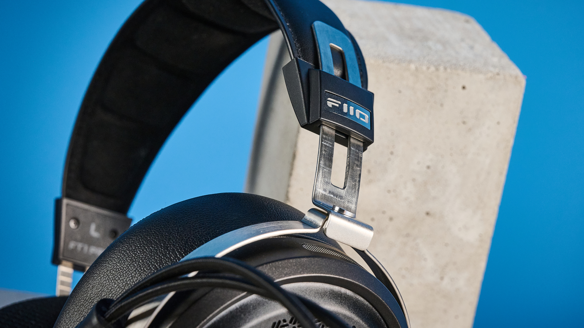 the fiio ft1 pro wired open-back headphones photographed with a blue tom's guide background