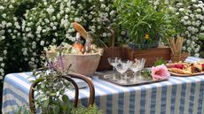 outdoor table set with glasses, food and a striped blue and white tablecloth