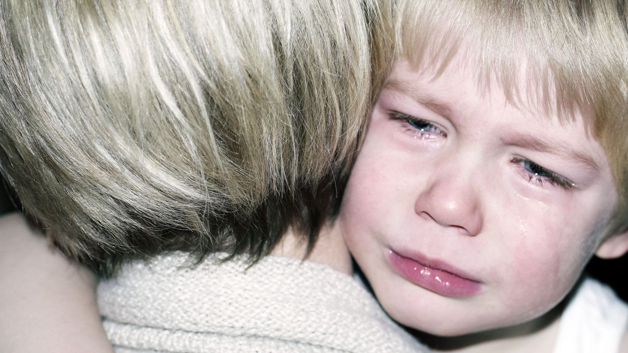 A child crying in a parent&#039;s arms.