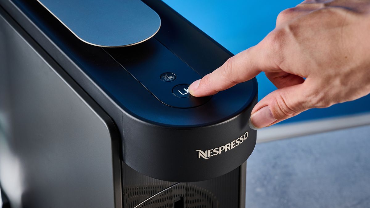 the nespresso vertuo up machine photographed against a blue background