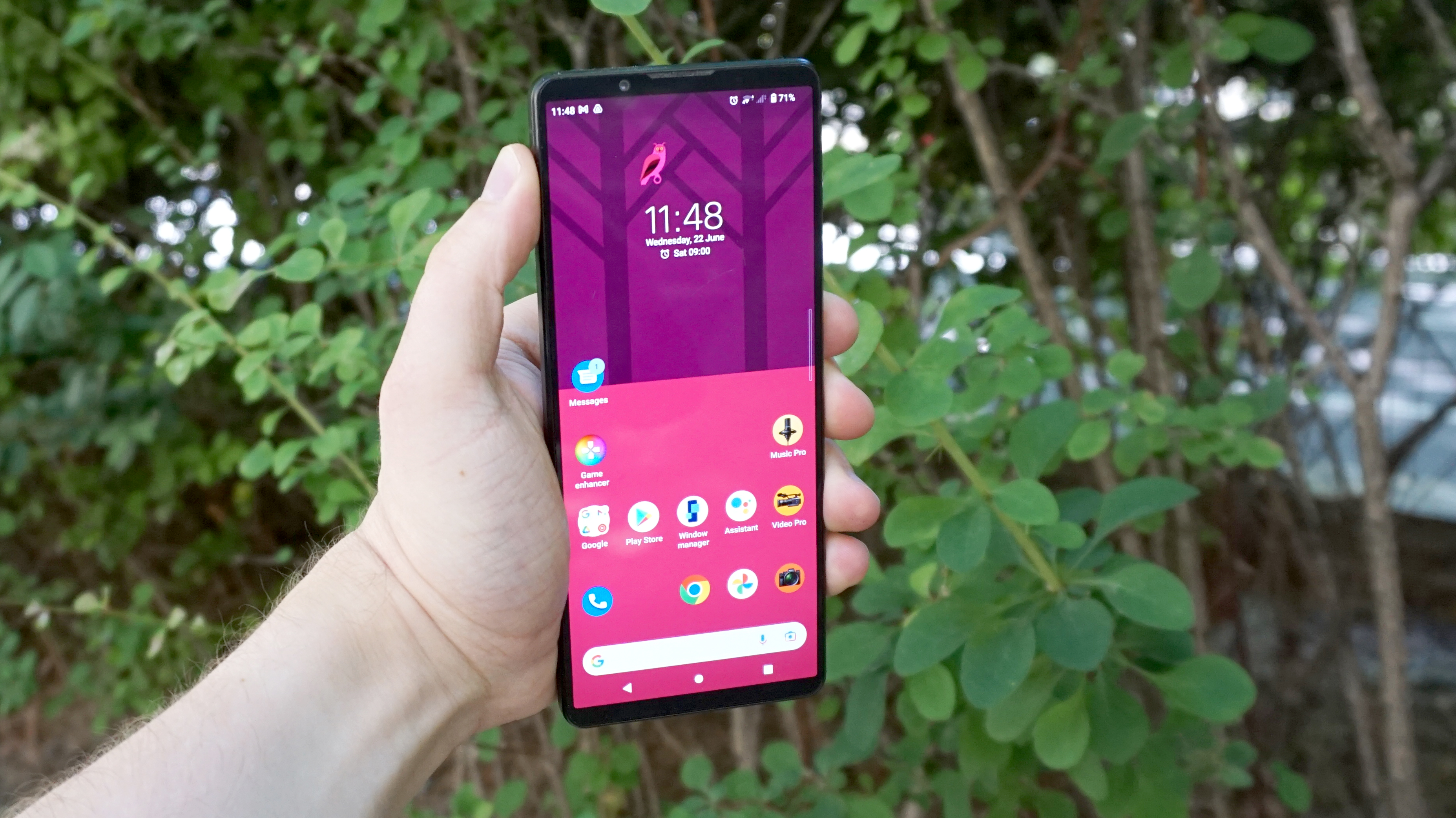 A Sony Xperia 1 IV in someone's hand, with foliage in the background