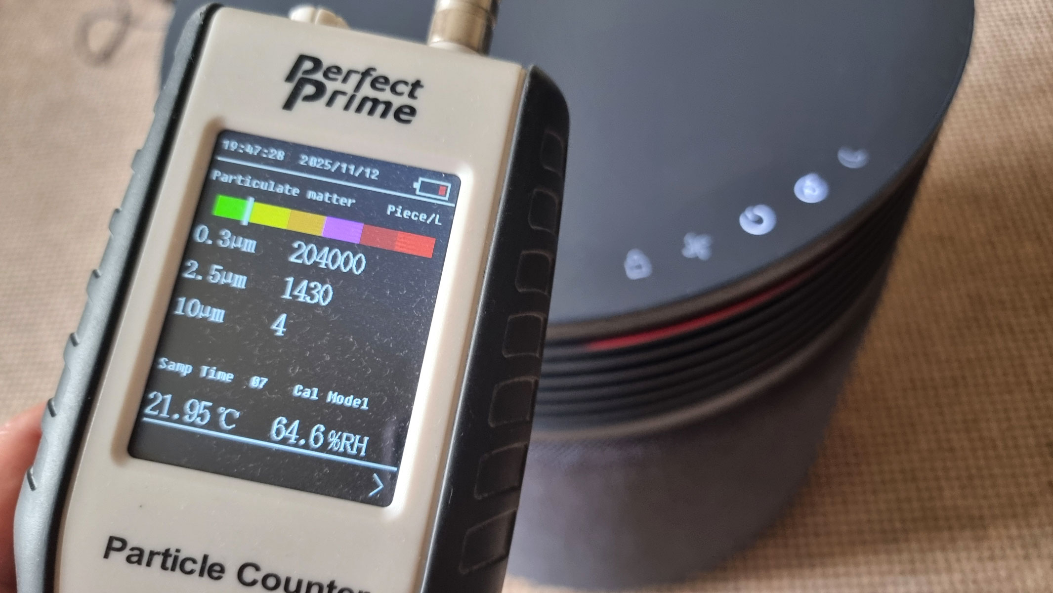 A close-up picture of our reviewer testing the Blueair Blue Signature air purifier using the Perfect Prime air particle monitor