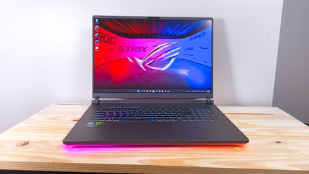 The Asus ROG Strix G18 with lid open on a wood table
