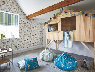 A playful childrens bedroom with safari themed wallpaper, bean bag chairs and a treehouse bed
